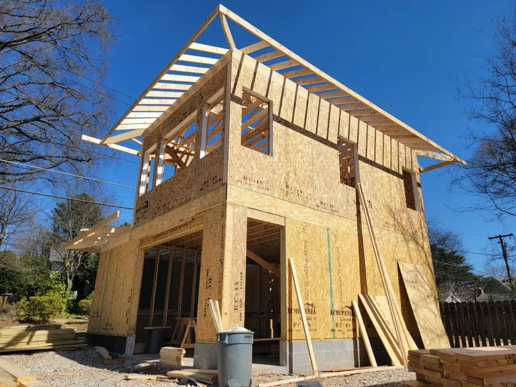 The two-story carriage house frame with roof trusses going on above SIP walls in Charlotte, NC