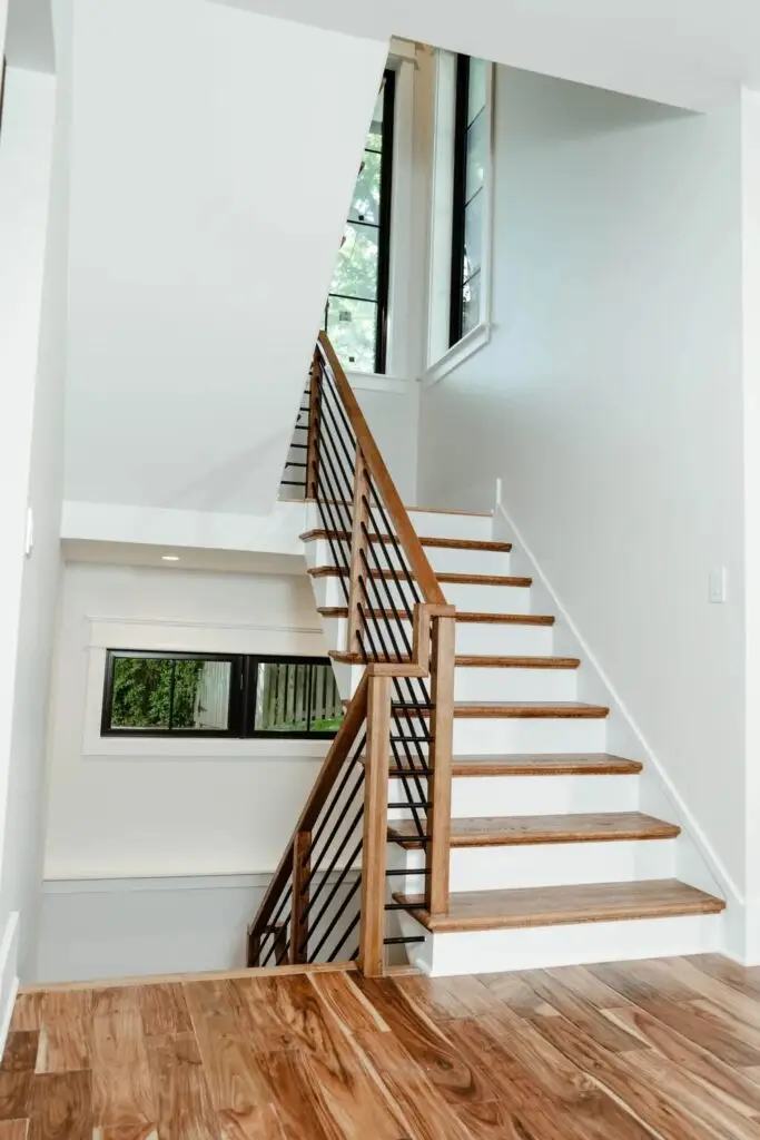 Wood staircase with metal railing and a tall window in a completed SIP home in Vienna, Virginia
