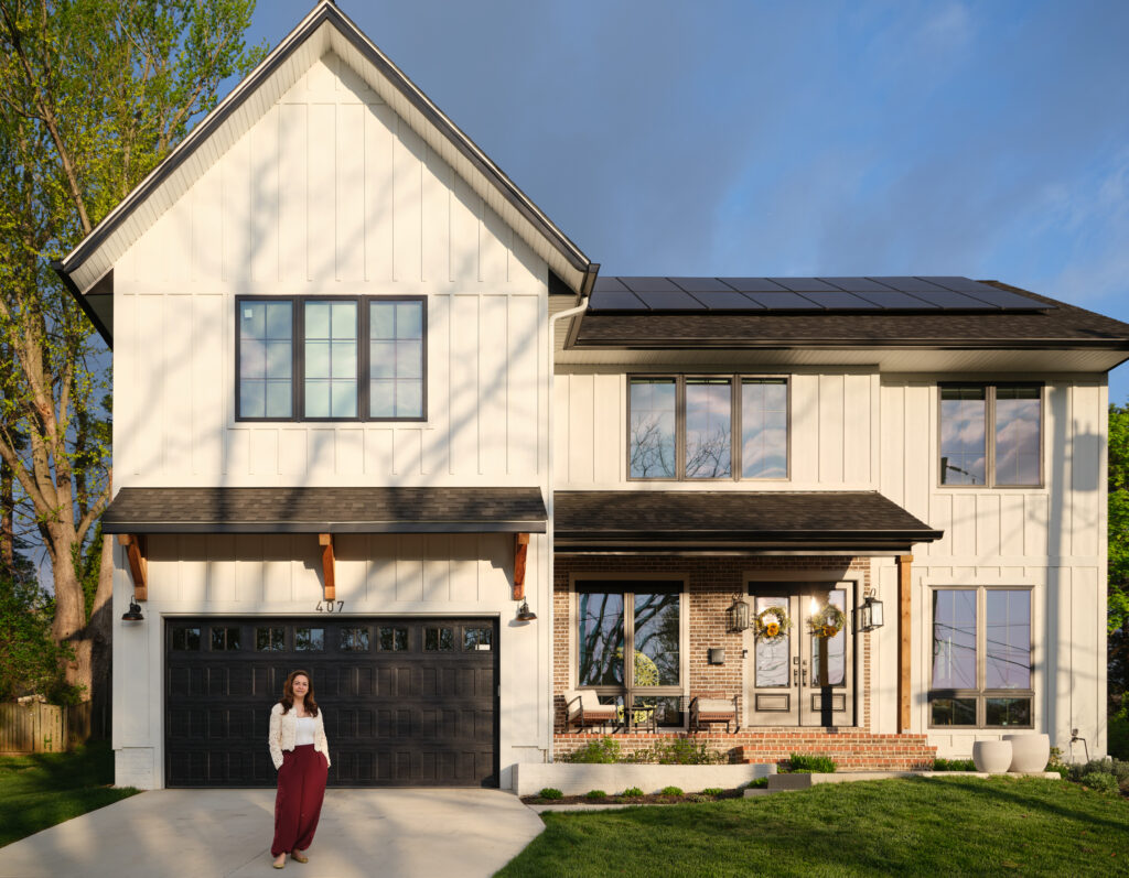 Completed DOE Zero Energy Ready SIP home in Vienna, Virginia with rooftop solar panels and the homeowner standing in the driveway