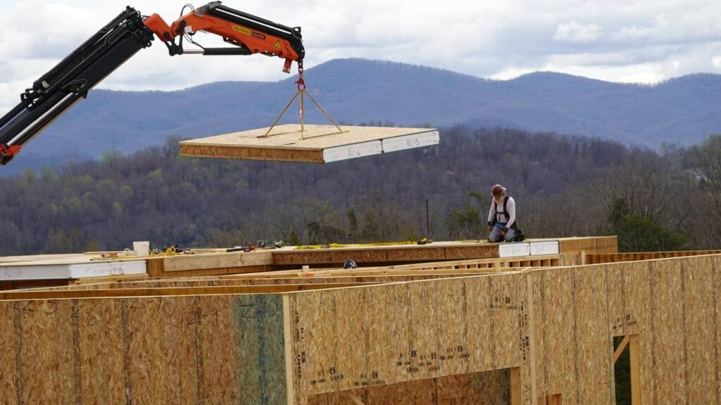 A crane lifting an ACME SIP roof panel into place during installation
