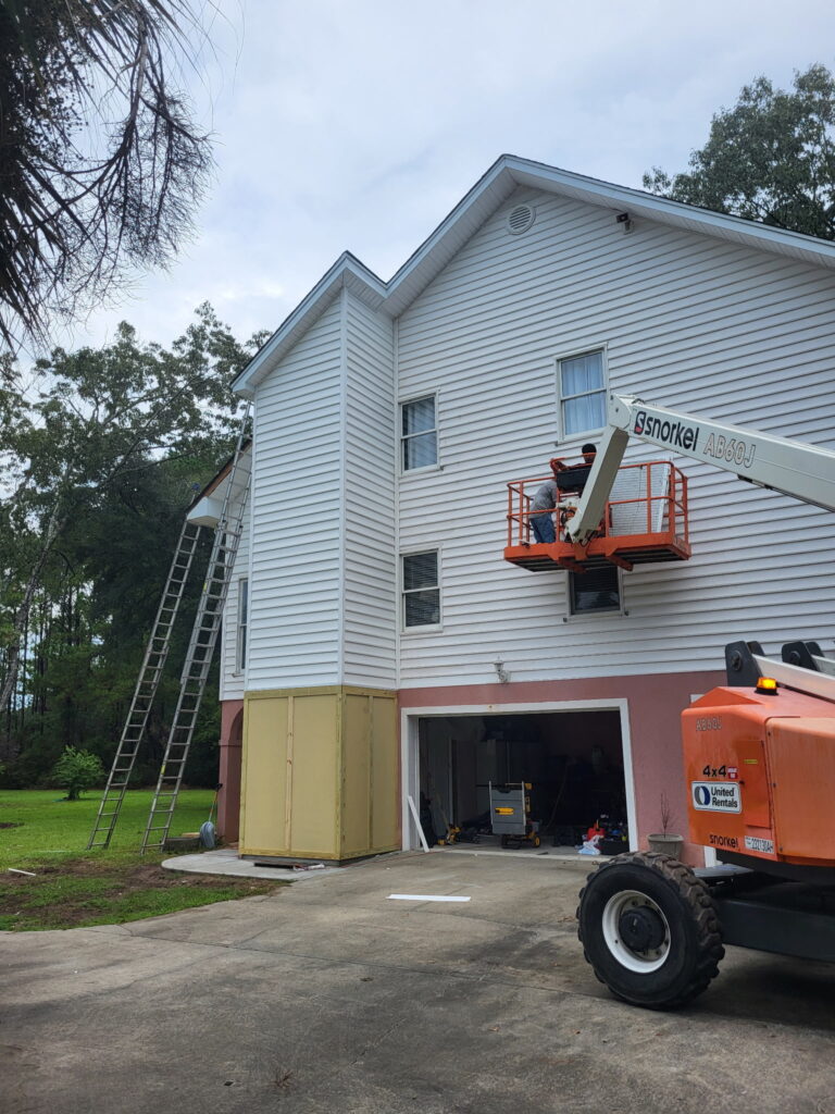 Exterior view of the 30-foot SIP elevator shaft addition under construction on a three-story home in Meggett, South Carolina, with OSB-sheathed SIP wall panels rising from foundation to roofline.
